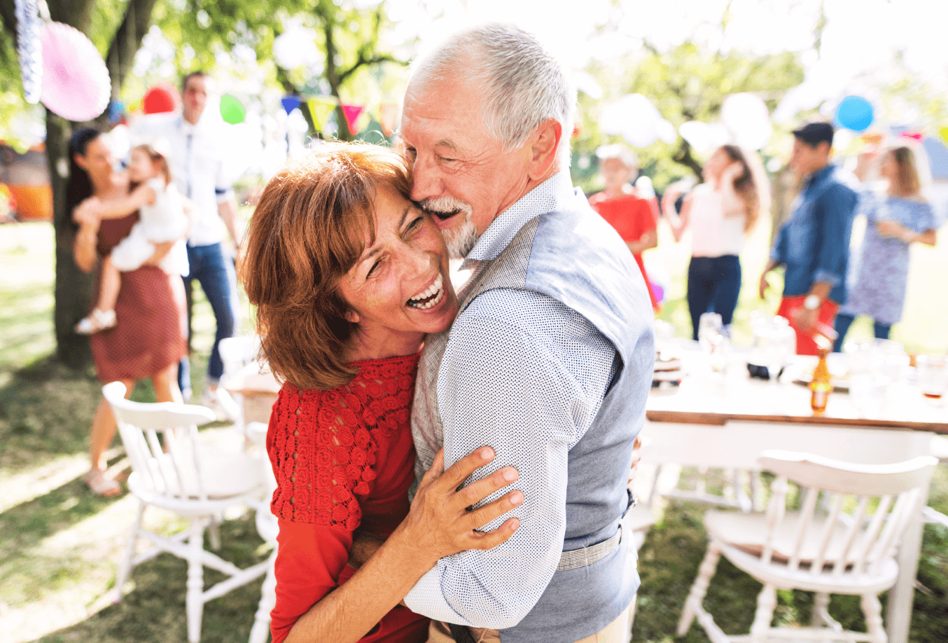 Elderly couple hugging at an outdoor party