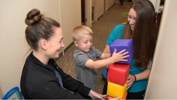 Physical therapist with young patient stacking blocks