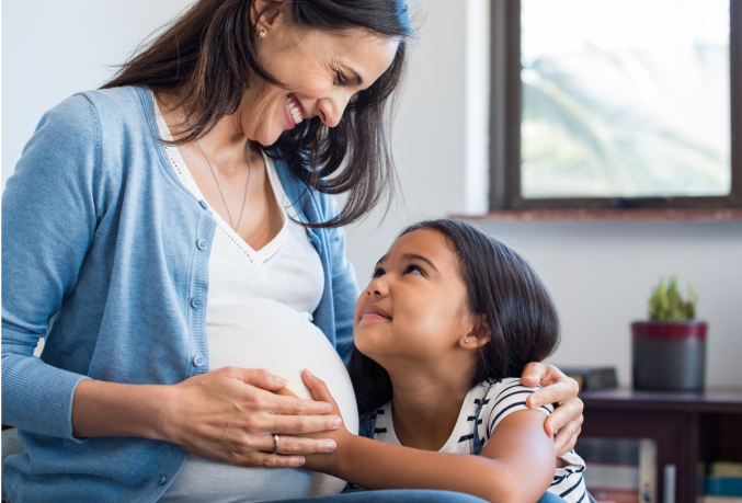 Woman holding pregnant belly and looking at ultrasound pictures