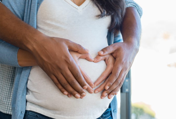 Couple with hands in shape of a heart on belly